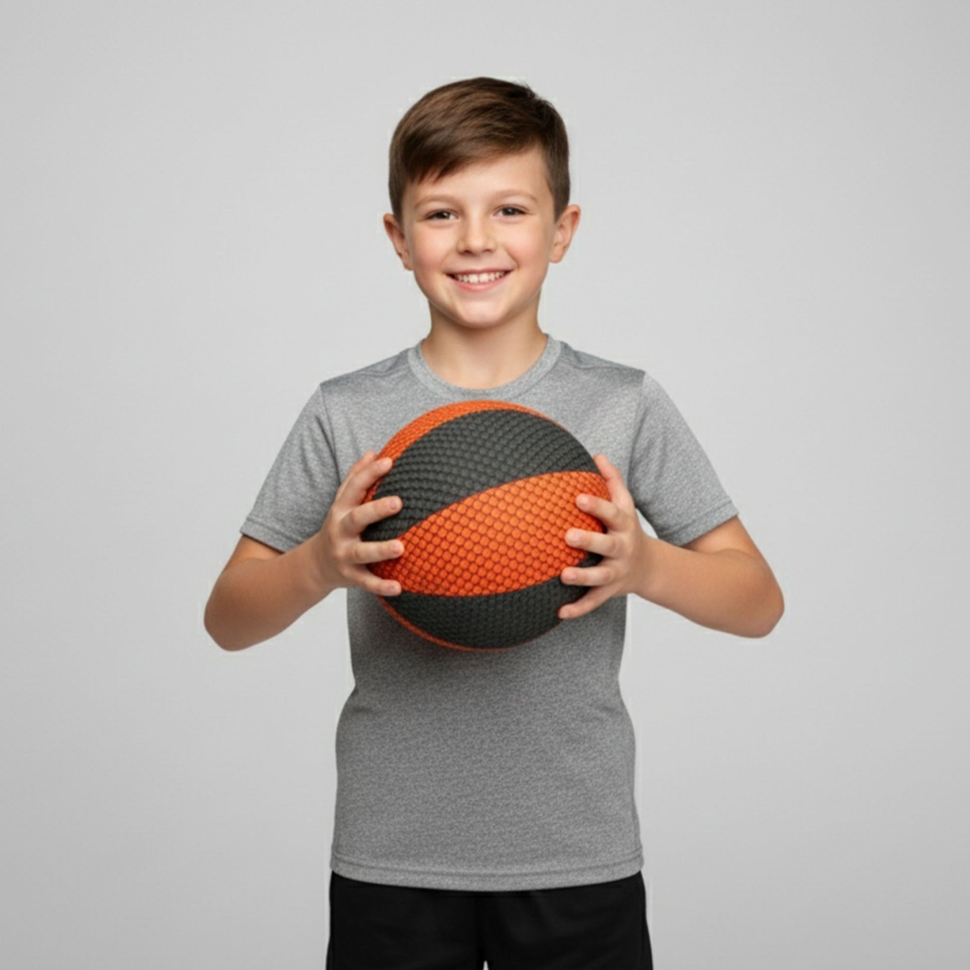 Child holding a black and orange ball against a gray background