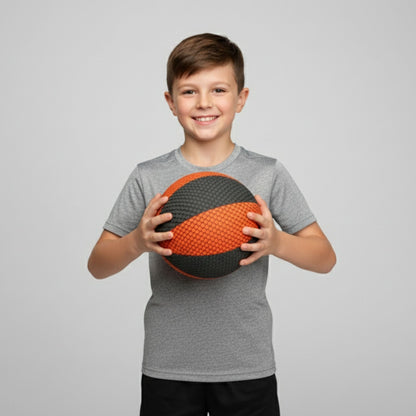 Child holding a black and orange ball against a gray background